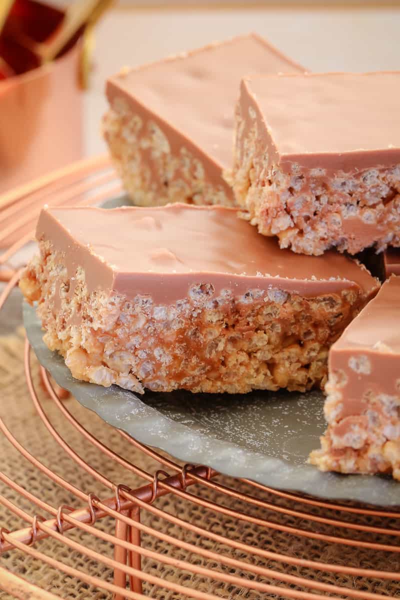 Pieces of crunchy rice bubble slice made with chocolate and caramel and topped with milk chocolate on a plate