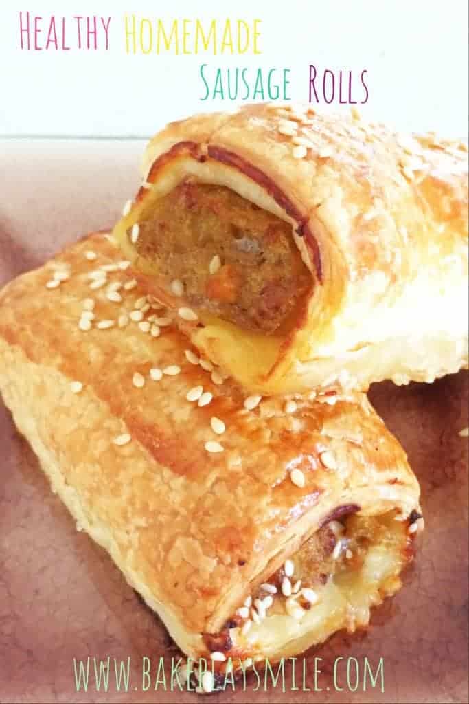 Two homemade sausage rolls of meat wrapped in pastry and sprinkled with sesame seeds.