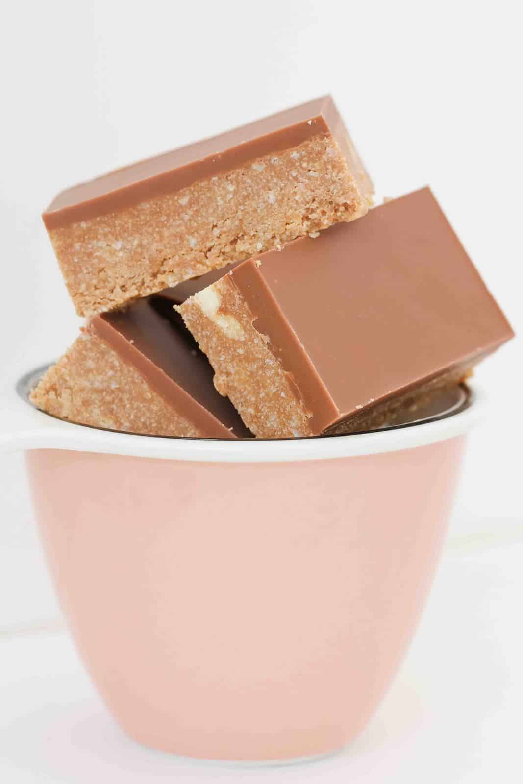 Pieces of no-bake chocolate slice with chocolate topping, stacked in a small bowl.