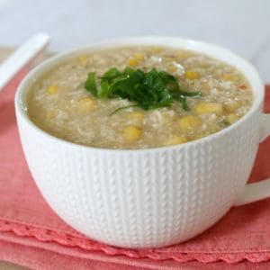 A soup mug filled with chicken and corn soup and garnished with chopped parsley