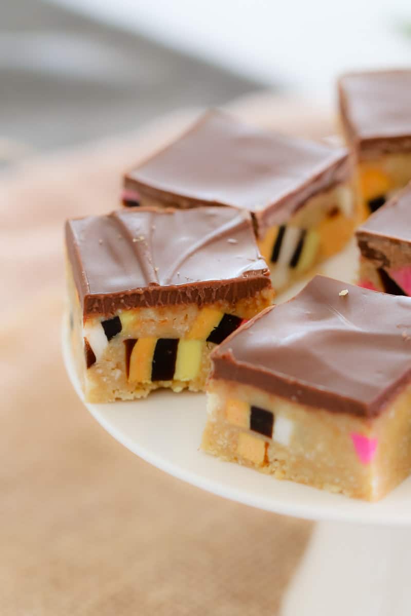 A close up of colourful slice squares topped with a layer of milk chocolate