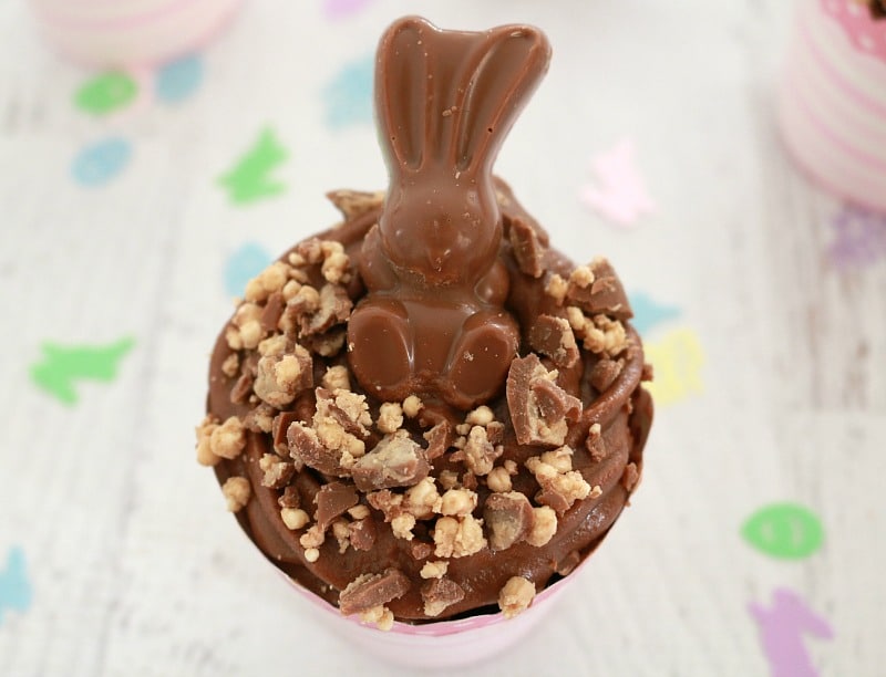 A Malteser bunny sitting on top of a chocolate easter cupcake. 