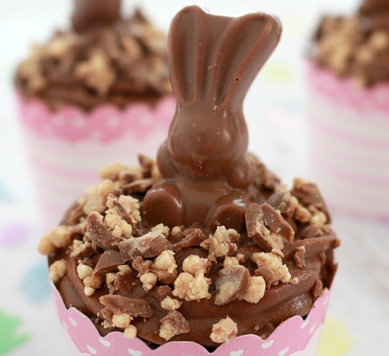 Malteser bunnies sitting on top of easter chocolate cupcakes. 