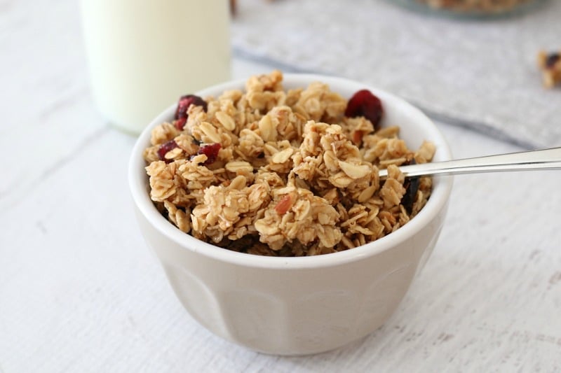 A small grey bowl filled with granola clusters with almonds and dried cranberries.