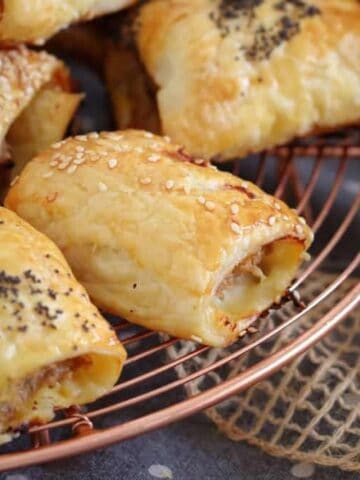 Flakey sausage rolls on a copper rack.