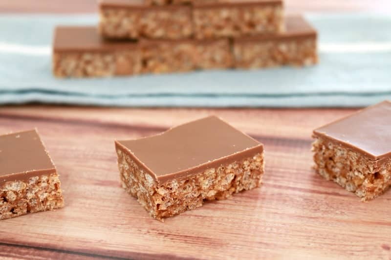 A piece of rice bubble slice with a chocolate topping on a bench