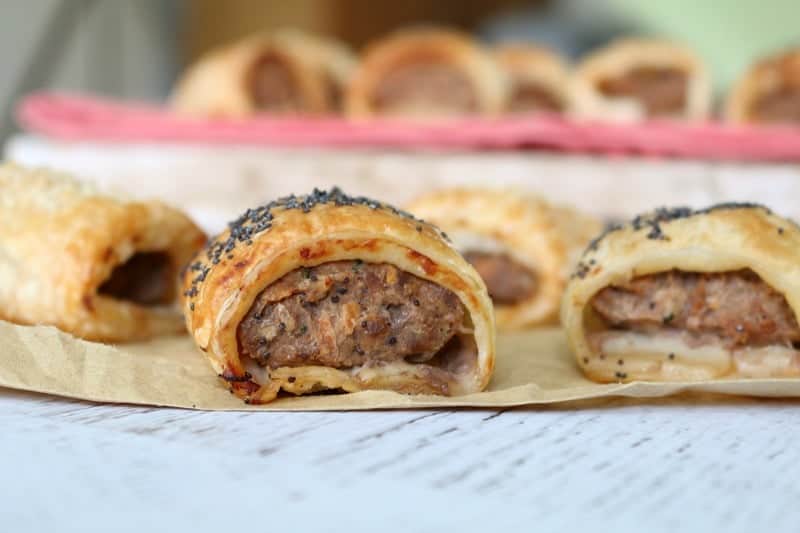 A close up front view of a classic beef sausage roll with poppy seeds on top