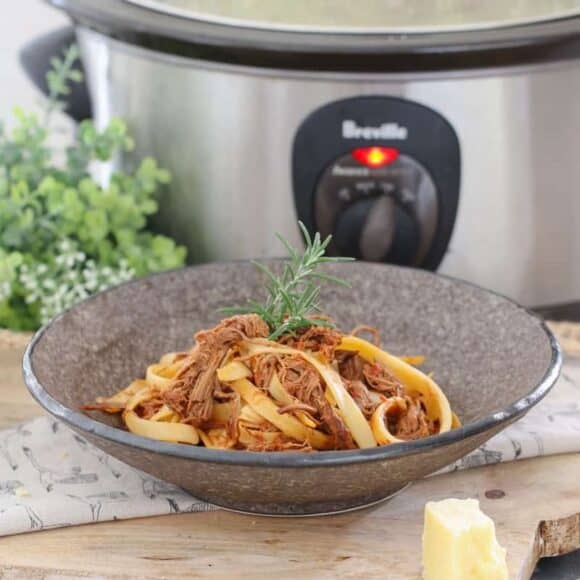A bowl of slow cooker Italian beef ragu pasta topped with parmesan.