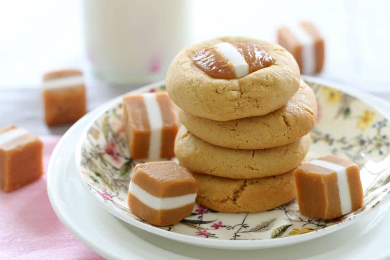 A stack of cookies with a jersey caramel baked on top, and loose Jersey Caramels on a plate