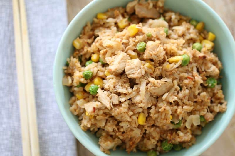 An overhead shot of fried rice with shredded chicken, peas and corn