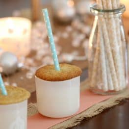 Cookies baked with vanilla and spices, placed on the top of white glass jars, with Christmas decorations in the background