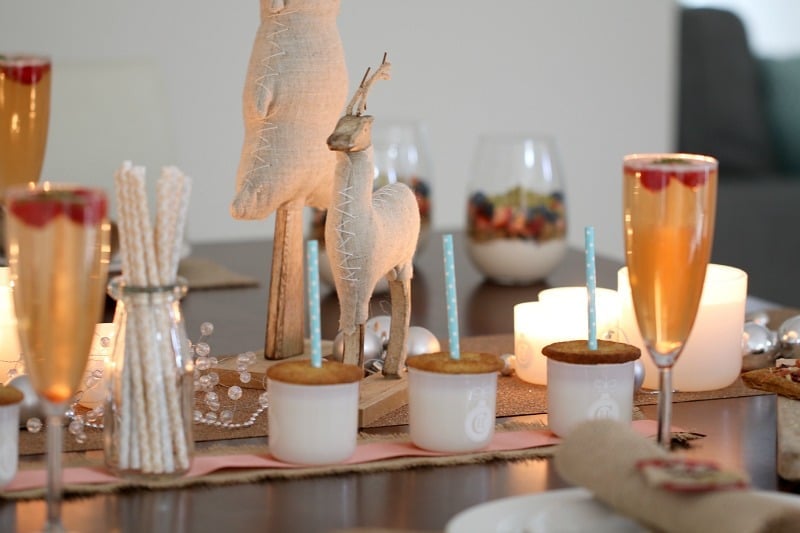 Christmas food and drink treats placed among wooden and fabric Christmas decorations and tea light candles