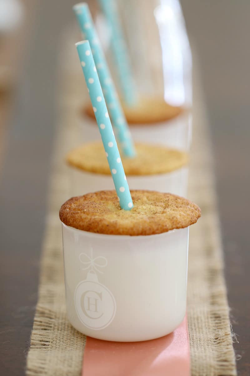 A close up of a Snickerdoodle cookie with a straw through the middle placed on top of a white glass jar