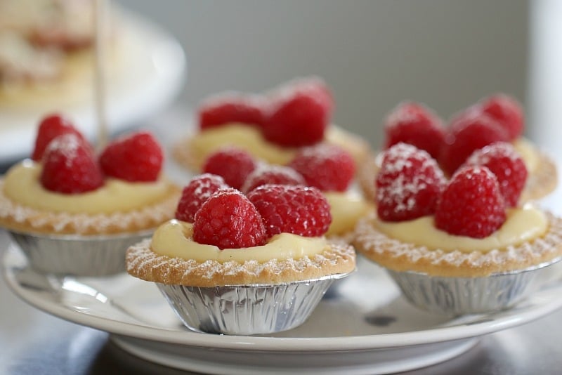 Vanilla custard tarts with fresh raspberries on top, served on a plate