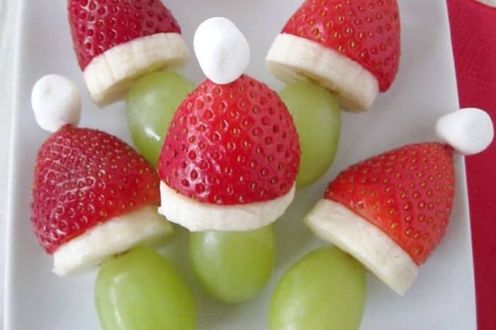 Fruit Santa hats made with a cut strawberry, and a slice of banana, on top of a green grape