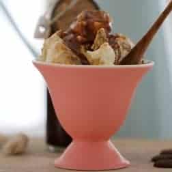 A pink sundae bowl filled with ice cream and Baileys sauce.