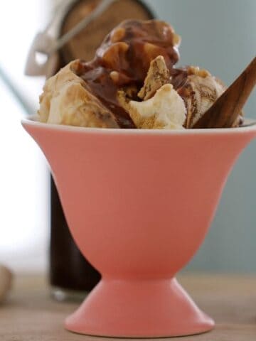 A pink sundae bowl filled with ice cream and Baileys sauce.