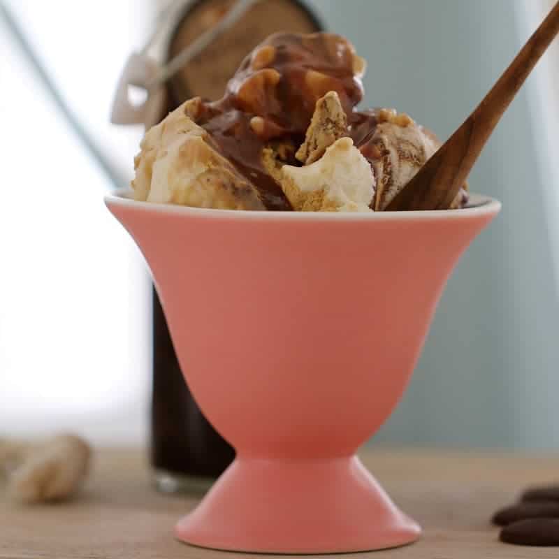 A pink sundae bowl filled with ice cream and Baileys sauce.