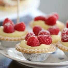 Mini custard tarts topped with fresh raspberries and dusted with icing sugar