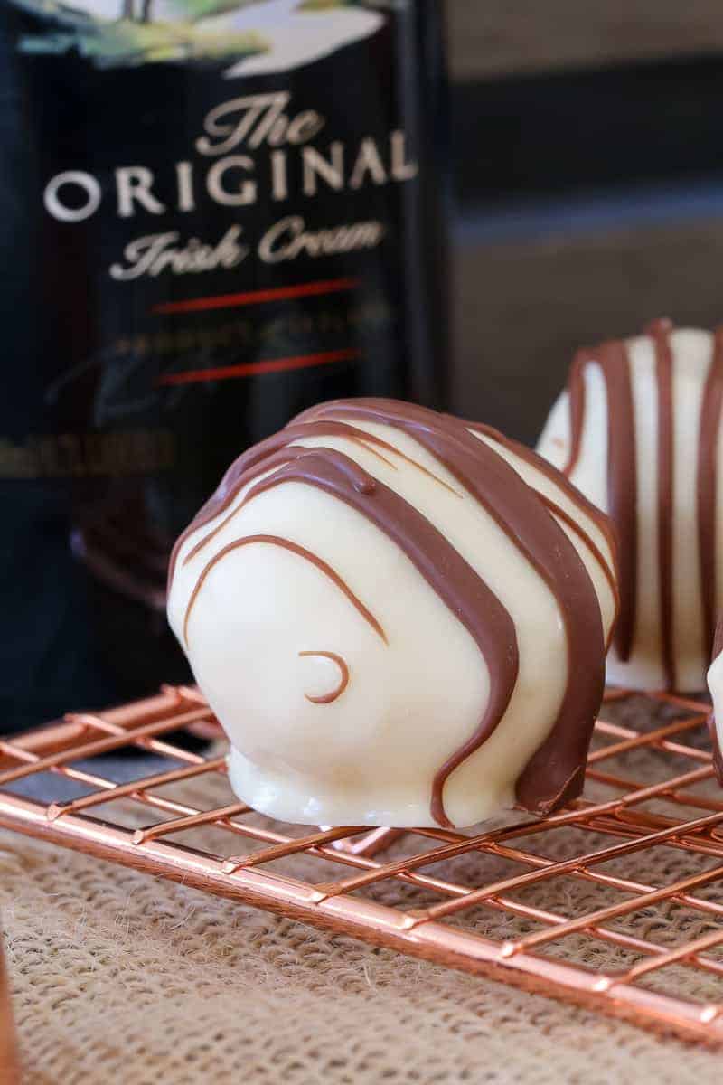 A Baileys cheesecake ball covered in white chocolate and drizzled with milk chocolate.