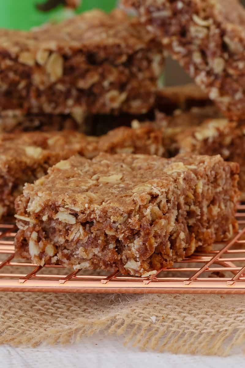 A close up of chocolate oat slice bars on a copper wire rack