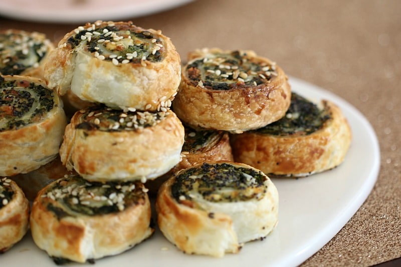 Baked spinach and feta pinwheel scrolls, piled on a serving board
