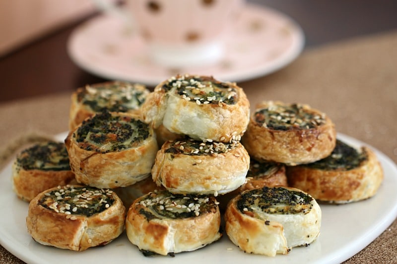 A pile of savoury pinwheel scrolls filled with spinach and feta