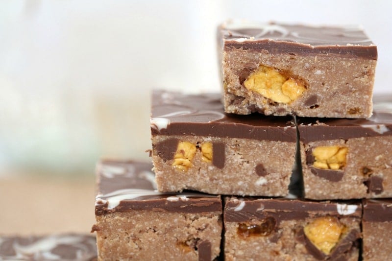 A close up showing chunks of honeycomb inside pieces of a chocolate topped slice