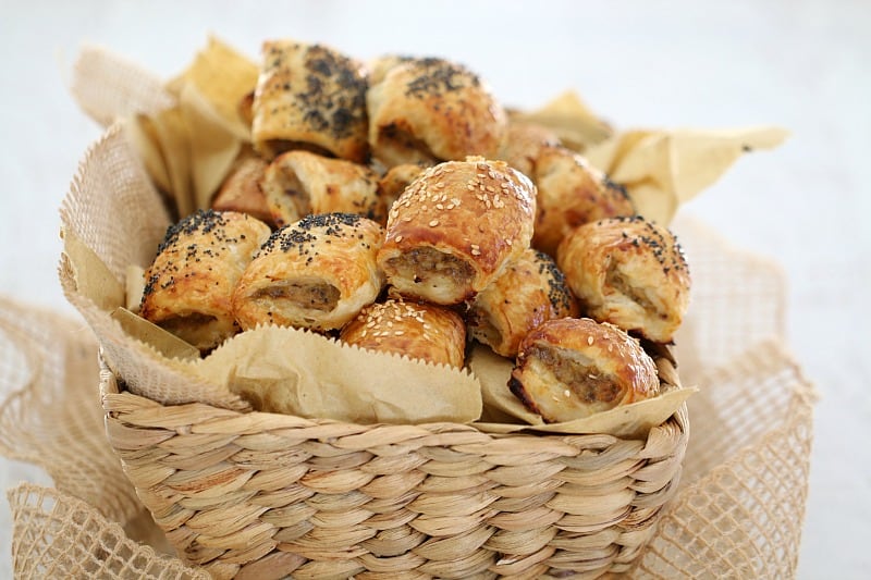 Golden puff pastry on mini sausage rolls piled in a basket