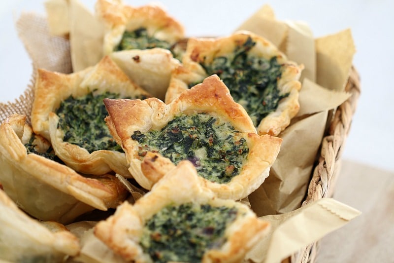 Spinach and ricotta tarts in golden puff pastry piled in a basket