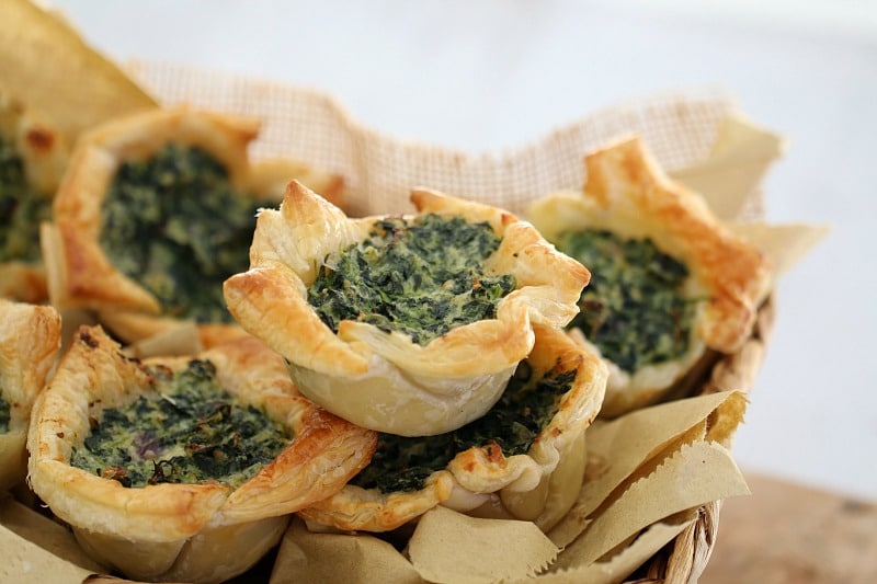 Puff pastry squares filled with spinach and ricotta piled in a basket