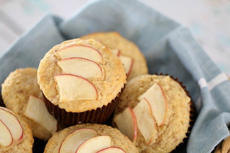 Slices of apple baked on top of muffins piled in a basket