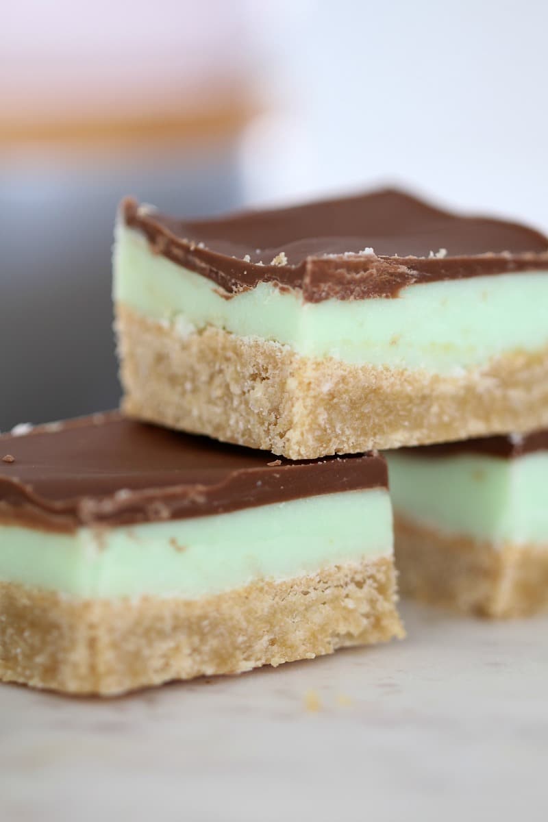 Three pieces of layered peppermint slice stacked on a plate