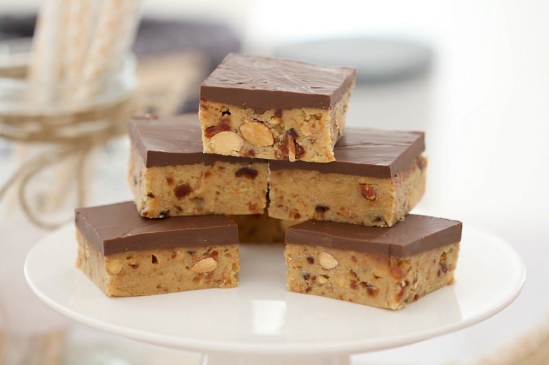 Squares of a date and almond filled slice with a layer of chocolate on top
