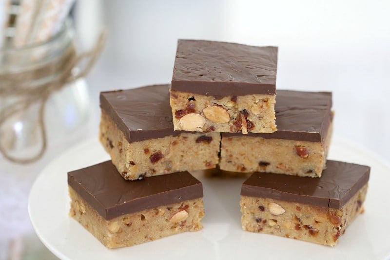 A stack of squares of a slice made with dates and almonds and topped with a layer of chocolate 