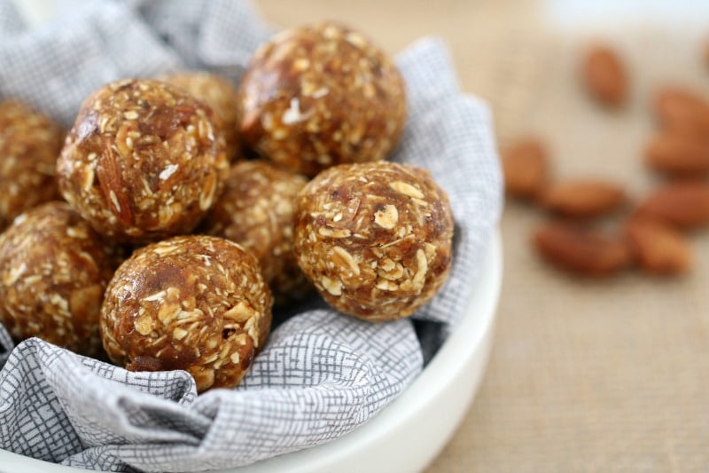 A close up of energy balls showing the oats and dates they are made of, piled in a small white bowl