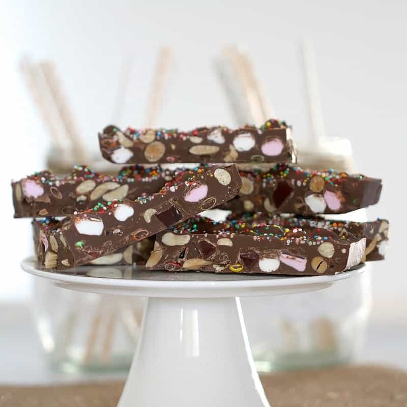 Pieces of Rocky Road filled with marshmallows, peanuts and Turkish Delight piled on a white cake stand