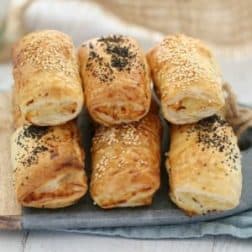 A pile of golden sausage rolls on a serving board