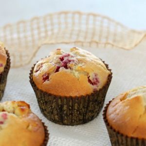 Magdalenas doradas en moldes para muffins, horneadas con frambuesas y chocolate blanco