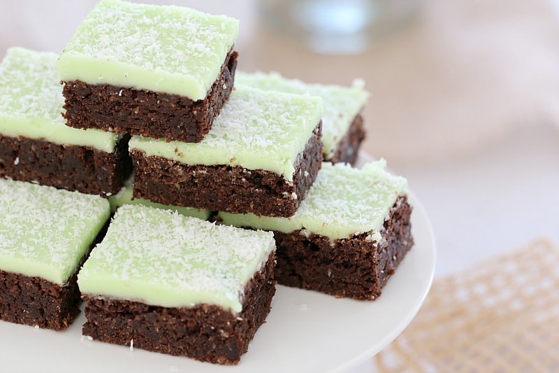 A close up of chocolate slices with mint icing and sprinkled with coconut