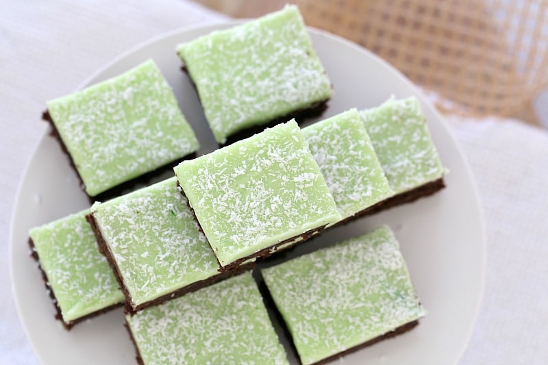 An overhead shot of pieces of chocolate slice, iced with a mint topping and sprinkled with coconut