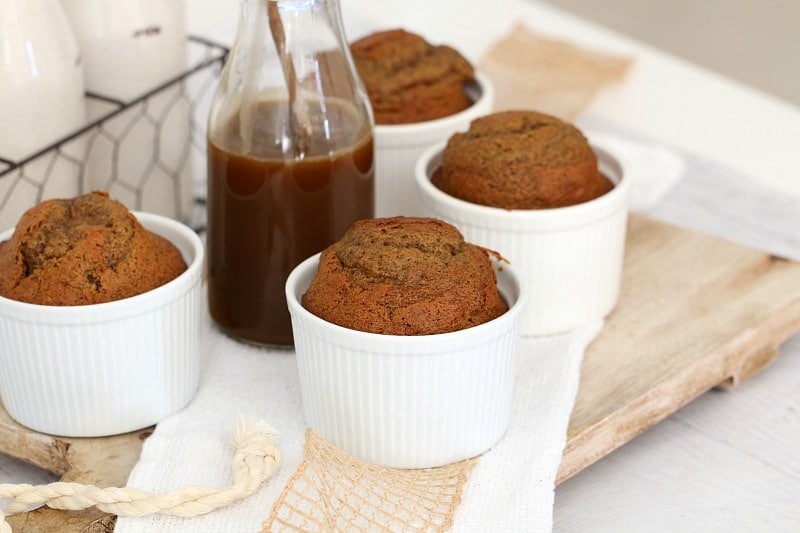 Sticky date puddings in small white ramekins and a bottle of caramel sauce