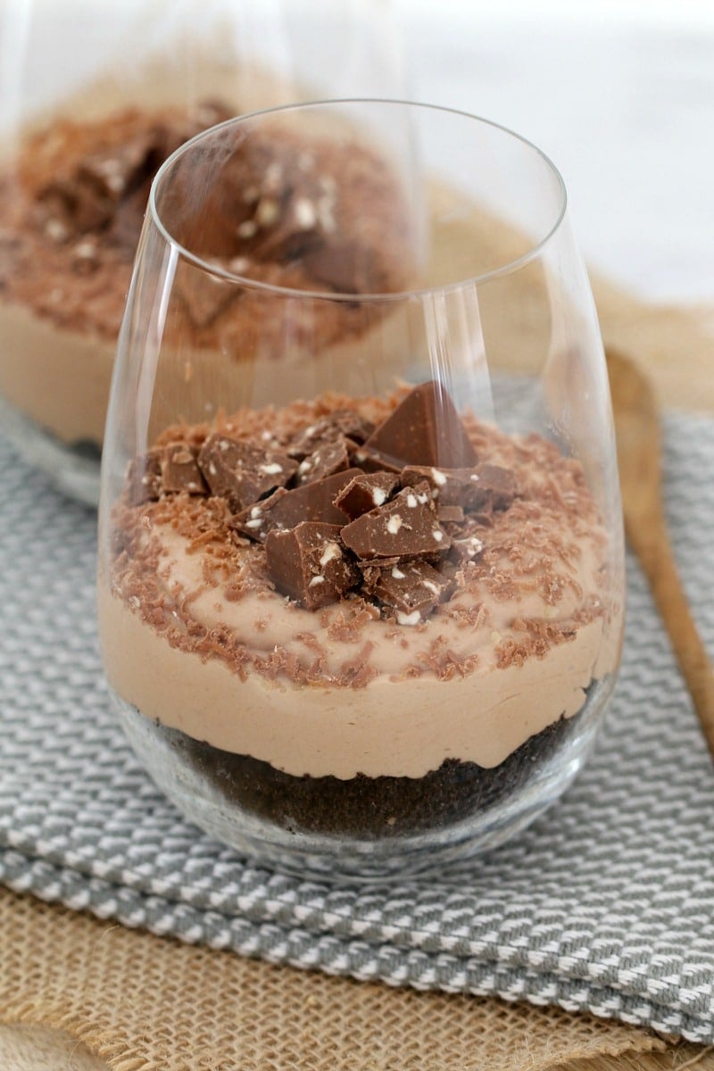 Close up of a glass filled with a chocolate cheesecake with chunks of Toblerone and grated chocolate on top.