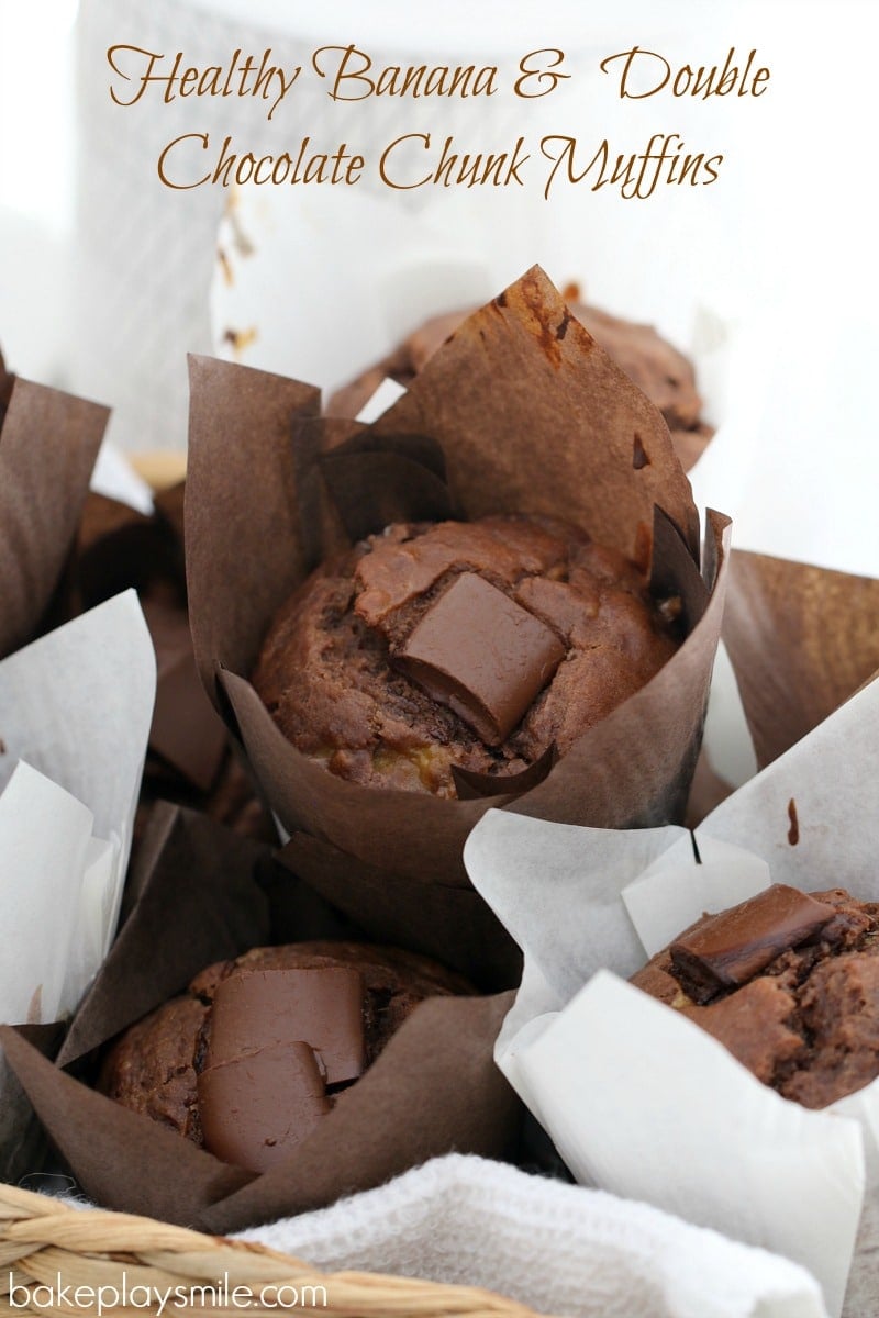 Chocolate muffins with chunks of chocolate on top and wrapped in baking paper piled in a basket