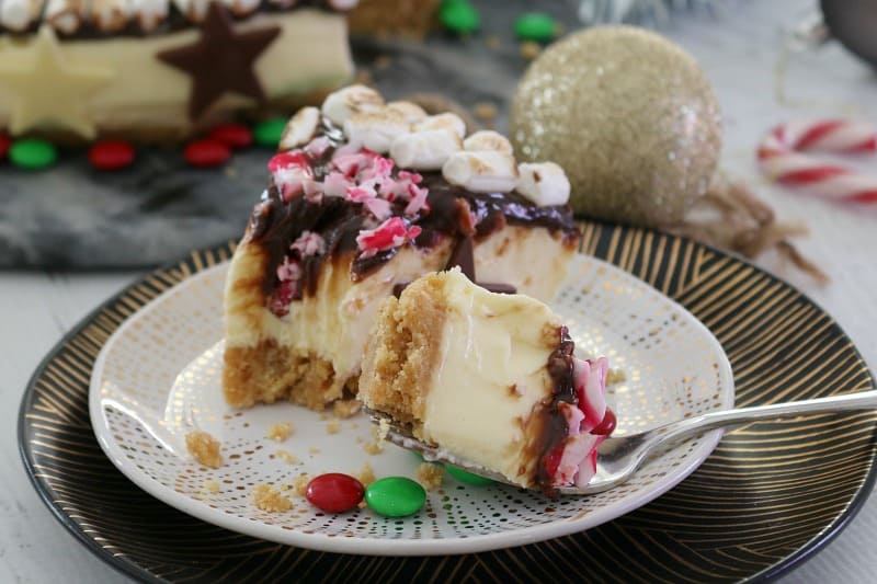 A slice of s'mores Christmas cheesecake with a forkful on a plate