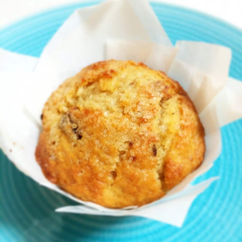 A muffin wrapped in baking paper sitting on a blue plate