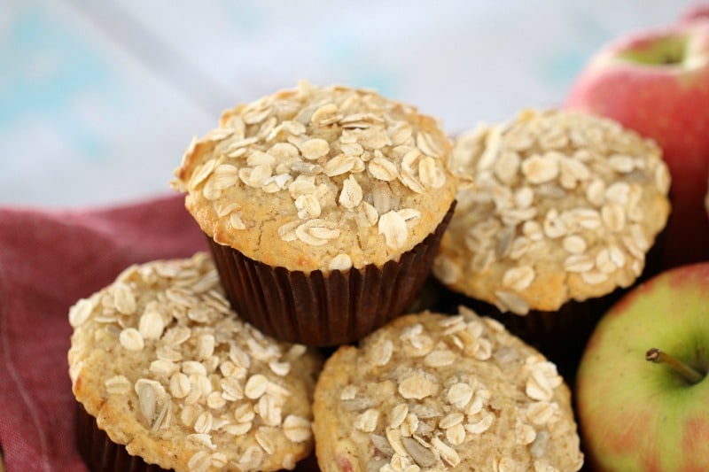 Muffins in brown baking cases topped with oats and stacked in a pile