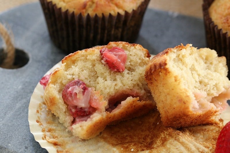 A muffin split to show filling of fresh strawberries inside