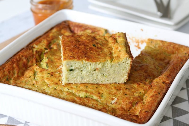 A baking dish filled with zuchinni slice with one piece cut and sitting on top to show texture