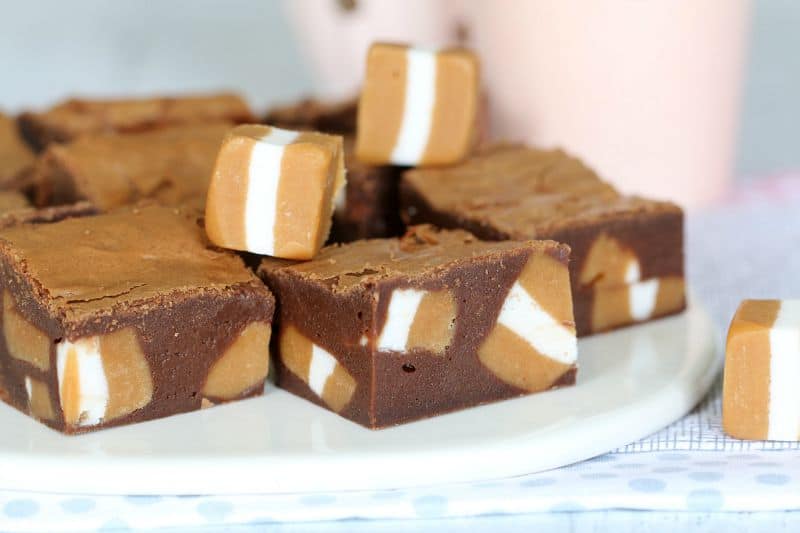 Pieces of a chocolate brownie showing chunks of Jersey Caramel inside, and some Jersey Caramel sweets sitting on top.